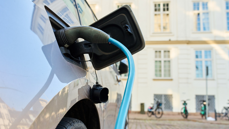 Close up of charging point on an electric vehicle with a street in the background